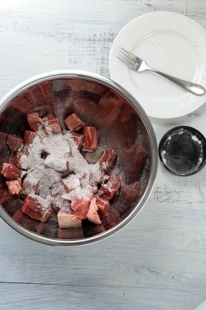 beef cubes with seasoning in a mixing bowl