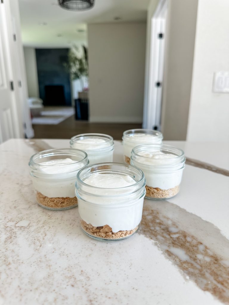 mini jars topped with cheesecake filling with a base of crushed graham crackers