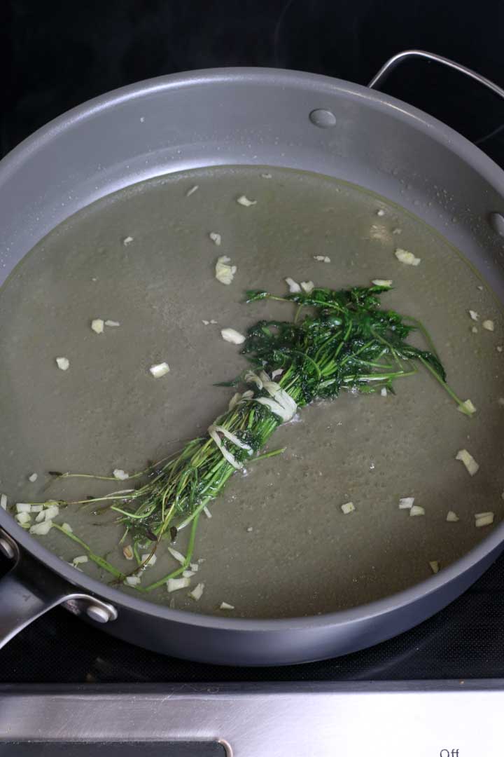 Bringing the herbs, garlic, and oil to a simmer.