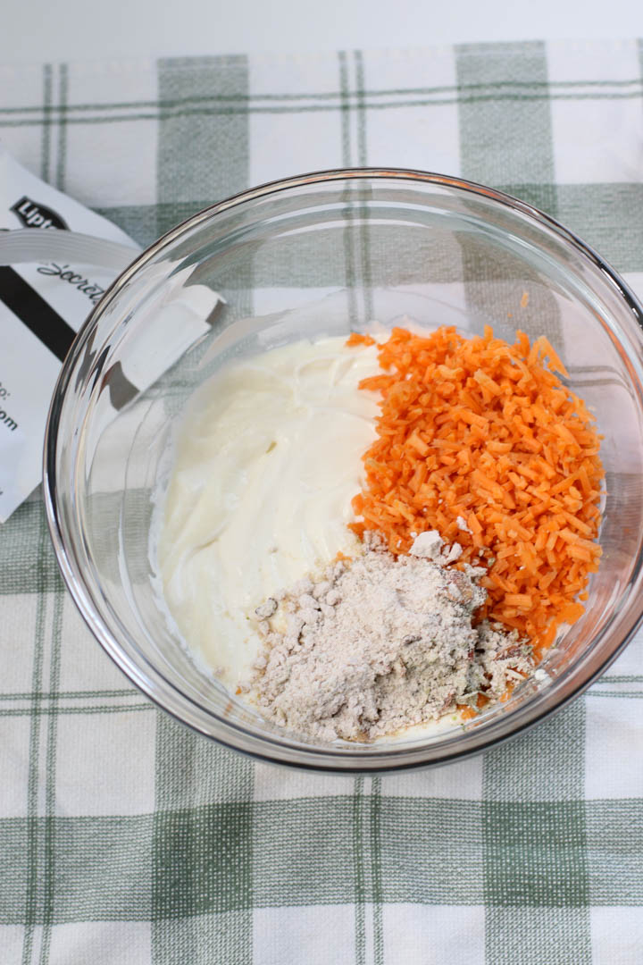 Adding grated carrots and seasoning packet to mixture.