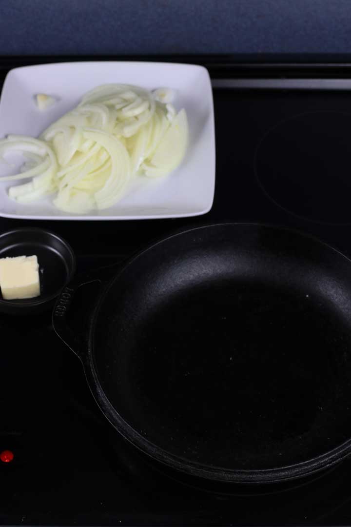 Butter, sliced onions, and a cast iron pan on the stove.